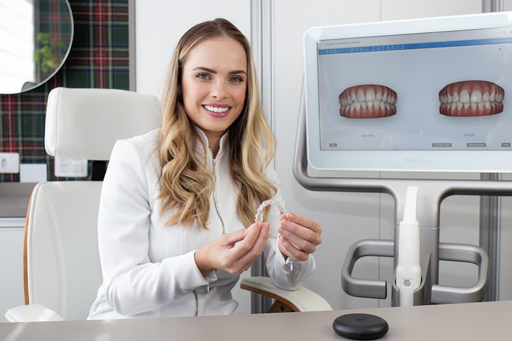 Dentist in Caledon at Caledon Dental Centre showing Invisalign clear aligners and digital 3D treatment plan to a patient in a modern dental office setting